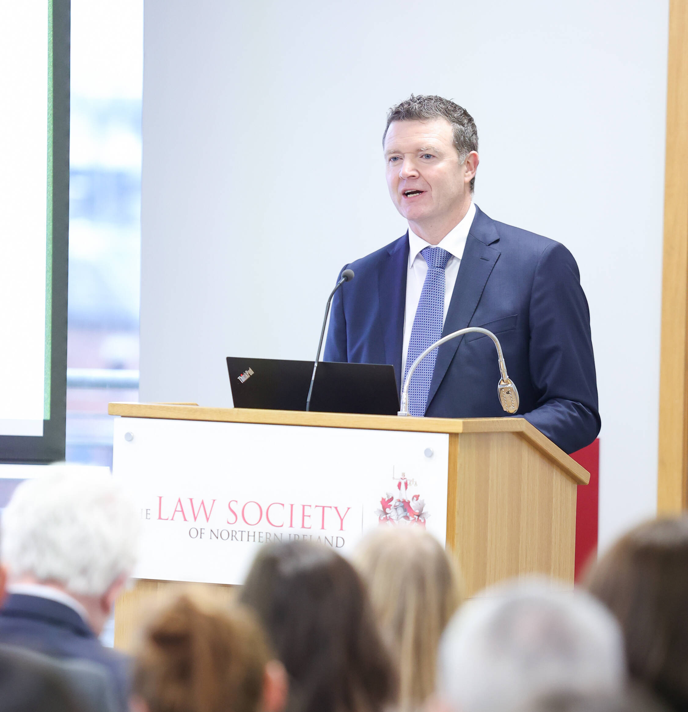 LSNI speaker stands at a podium addressing an audience