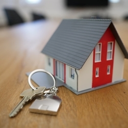 A small house figurine with keys next to it