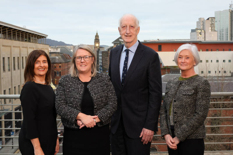 4 professionals standing on a balcony in front of a city skyline