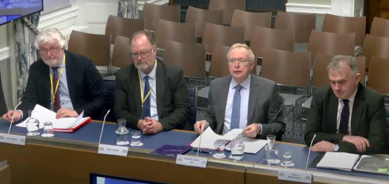 Four gentleman seated at a desk presenting as a panel