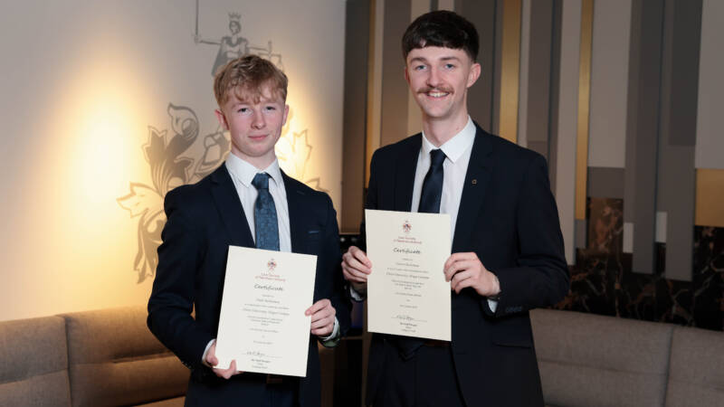 Two people holding certificates indoors