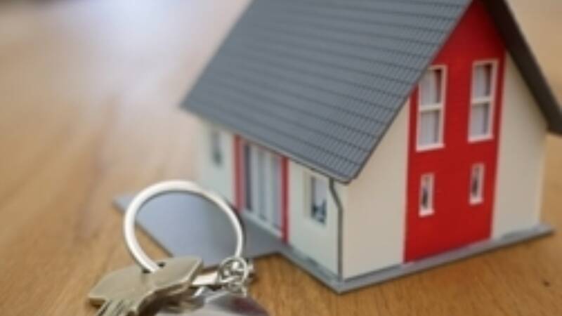 A small house figurine with keys next to it