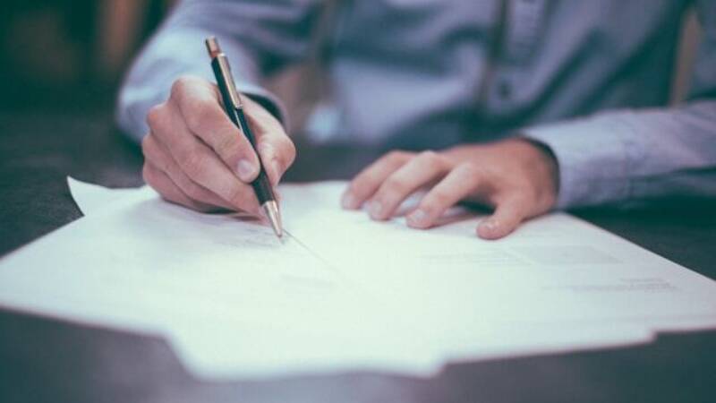A person's hands writing on a document