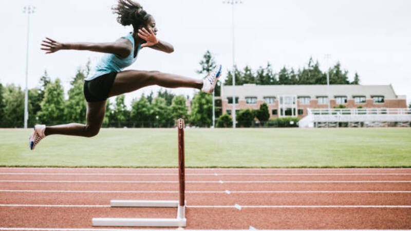 Athlete jumping mid air over a hurdle on a race track