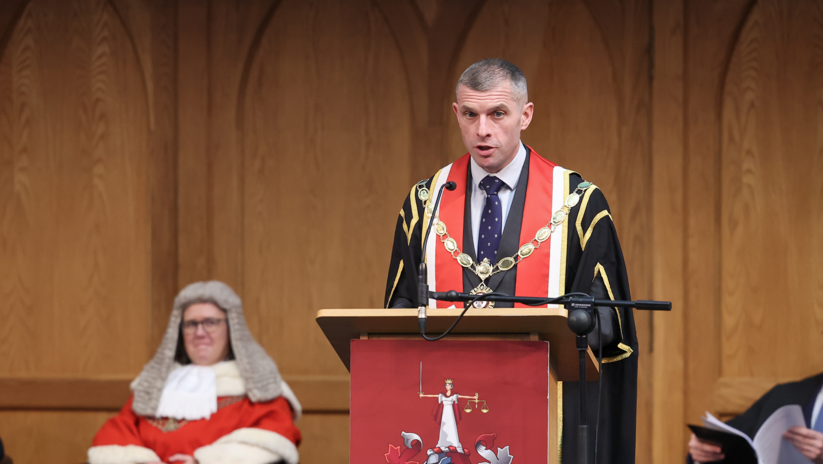 LSNI President Darren Toombs stands at a podium addressing an audience