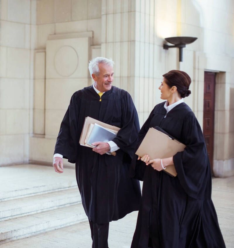 2 lawyers walking together and chatting while wearing robes