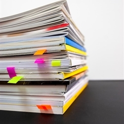Several books stacked on each other with sticky notes poking out of them