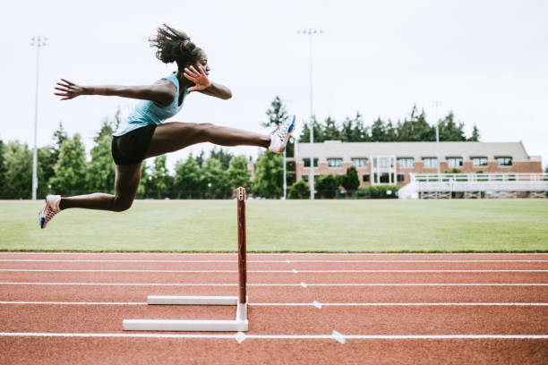 Athlete jumping mid air over a hurdle on a race track