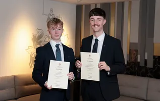 Two people holding certificates indoors